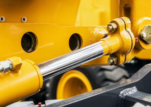 Close-up of a hydraulic piston and joint mechanism on a yellow construction machine